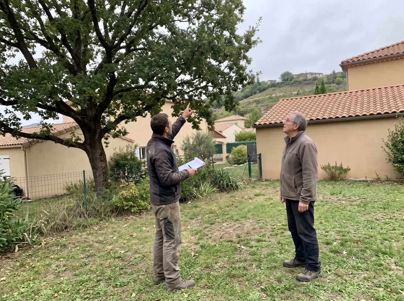 L'artisan explique l'intervention au client sous l'arbre